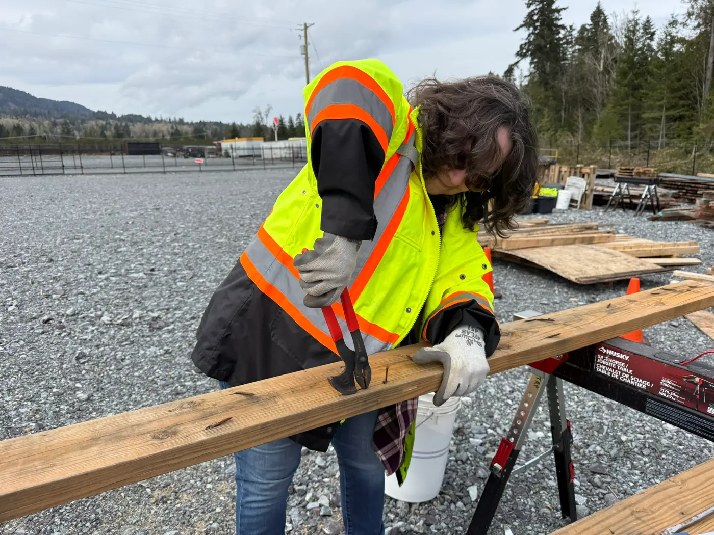 A volunteer preparing reclaimed lumber for reuse by removing nails and hardware.
